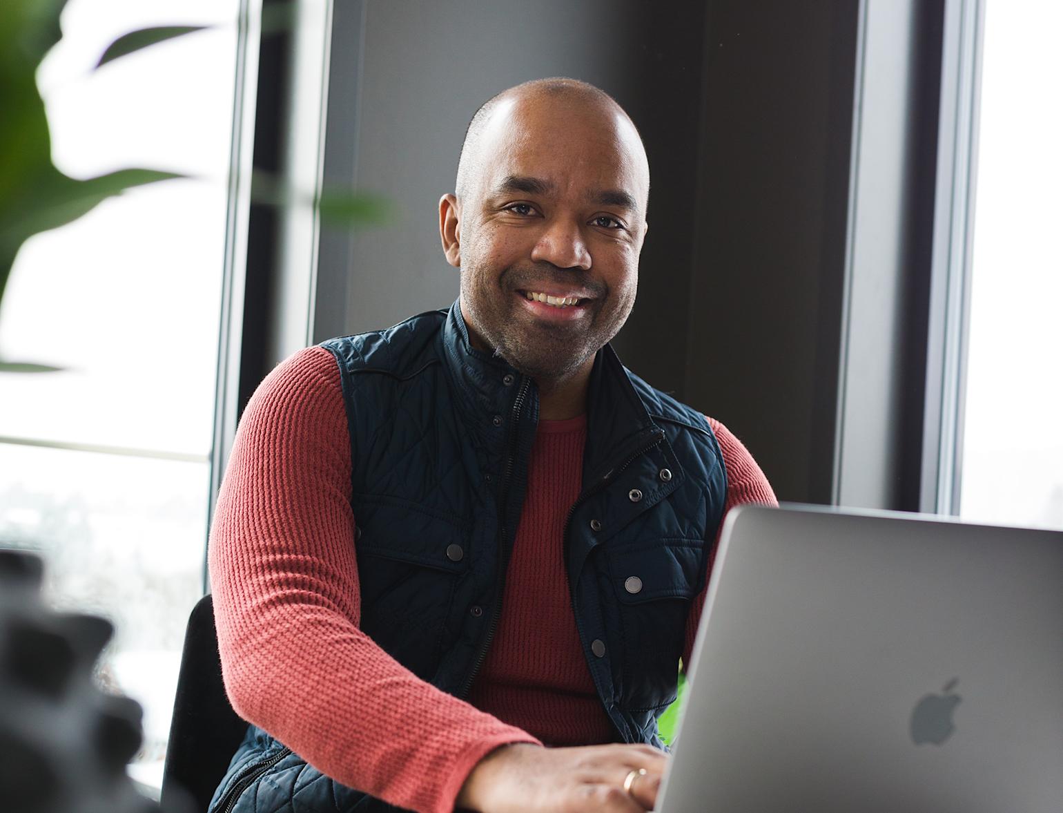 Kvinne ser på mobilen sin og smiler i stuemiljø