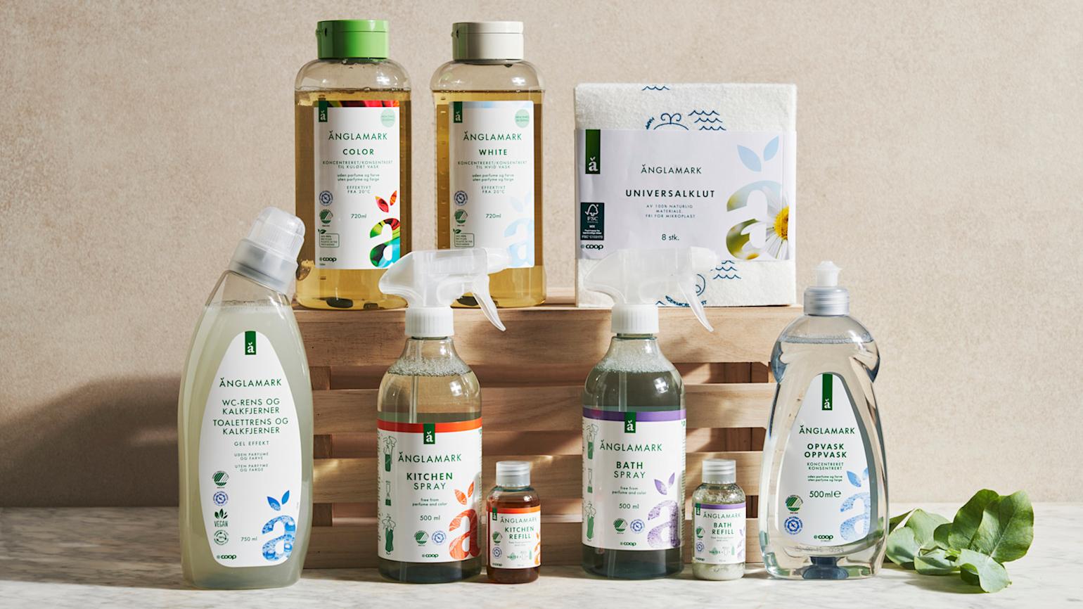 Et utvalg Änglamark rengjøringsprodukter i varm og lys setting, plassert på marmorbenk og lys trekasse. Vaskemiddel, tøyvask, toalettrens, oppvaskmiddel og universalkluter.
