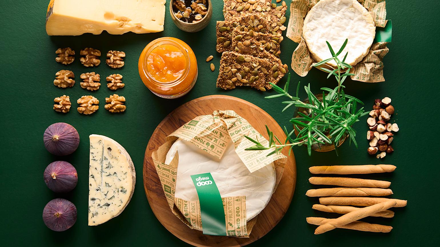 Forskjellige oster, kjeks, frukt, nøtter og urter på Mega grønn bakgrunn.