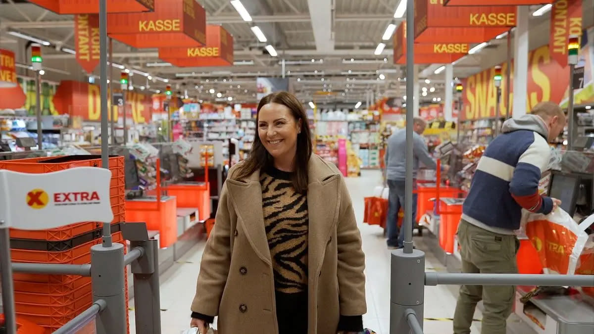 Smilende kvinne på vei ut av butikken