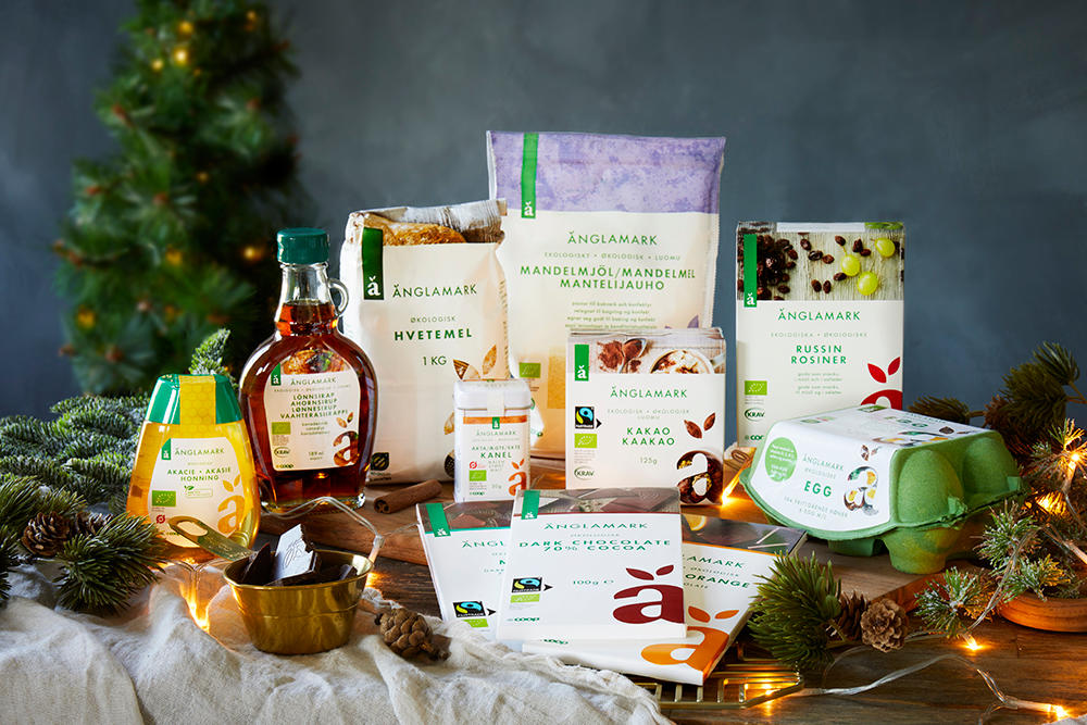 Utvalg av Änglamark produkter - alt du trenger til økologisk julebakst, presentert på mørkt trebord med julelys rundt.