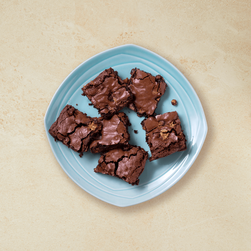 Snickers-brownie delt opp i biter, ligger på en blå tallerken