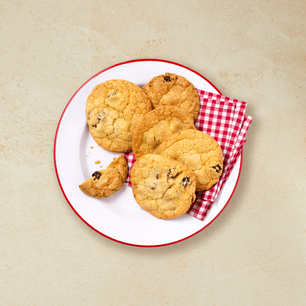 Cookies med pepperkake, sjokolade og rosiner servert på en rød- og hvitrutet serviett på rødkantet hvit asjett.