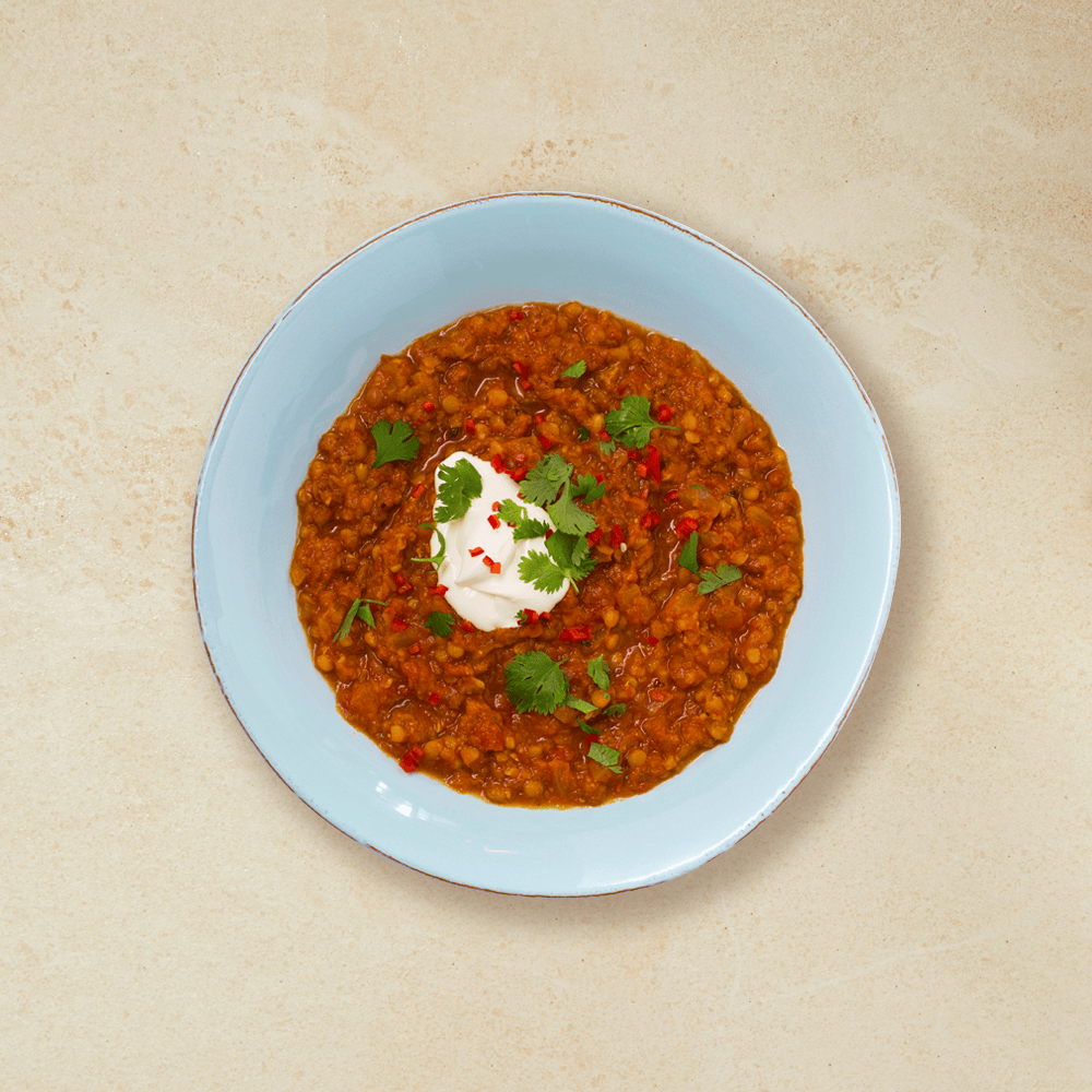 Hot linsesuppe med creme fraiche, koriander og chili, i en blå skål